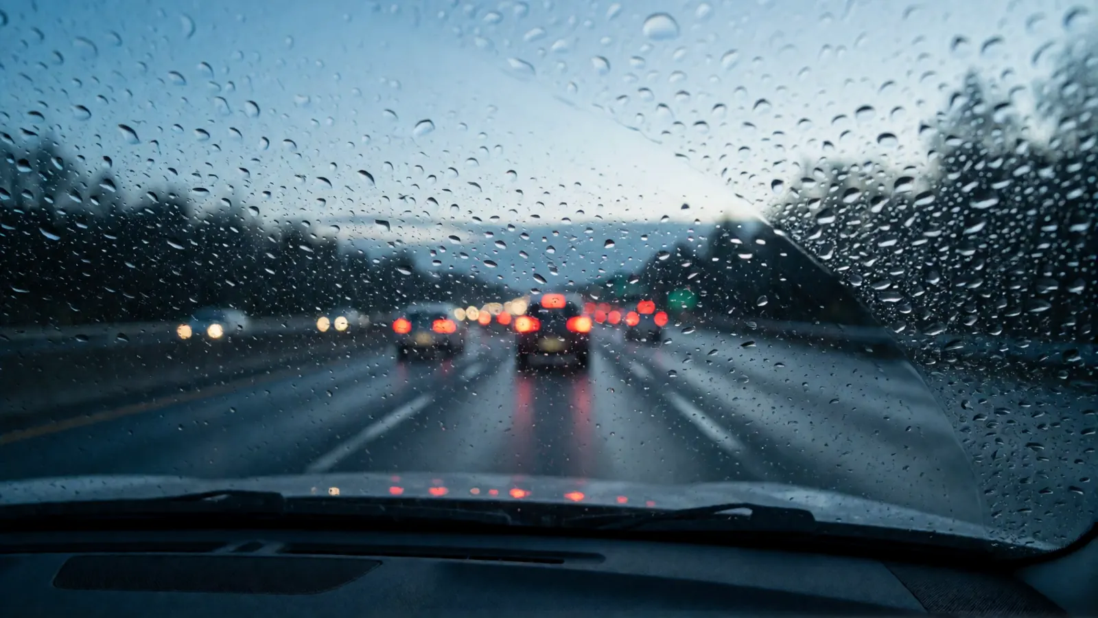 Highway at dusk in light rain seen through the windshield